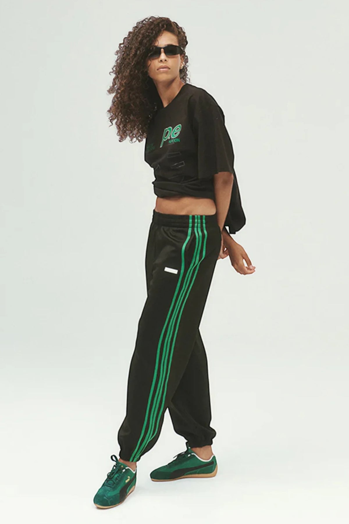 ELSHAM BOUTIQUE black track pants with green side stripes, elastic waistband, and cuffed hems worn by a model.