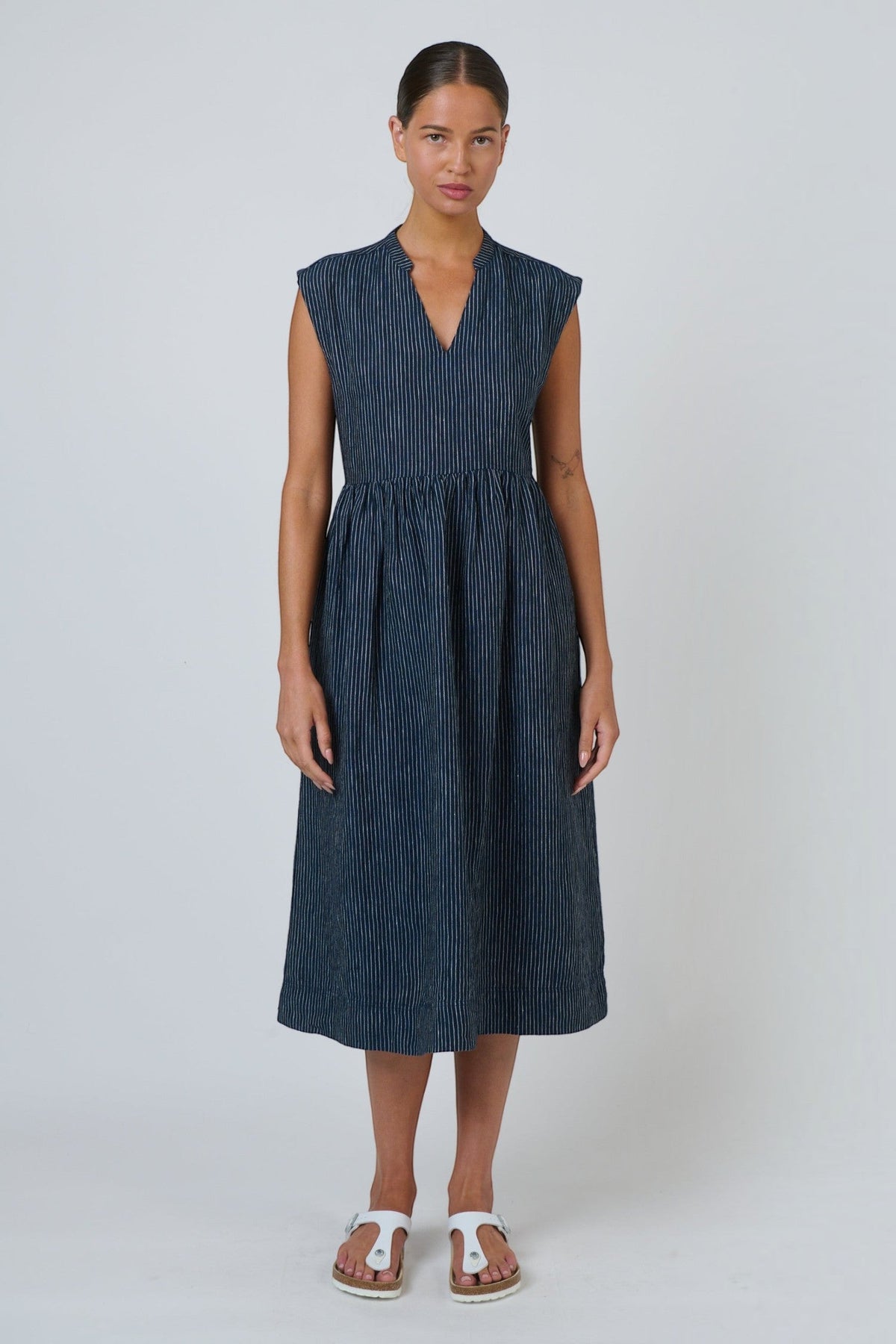 ELSHAM BOUTIQUE navy pinstripe linen midi dress with V-neck, cap sleeves, and drop gathered waist on a model.