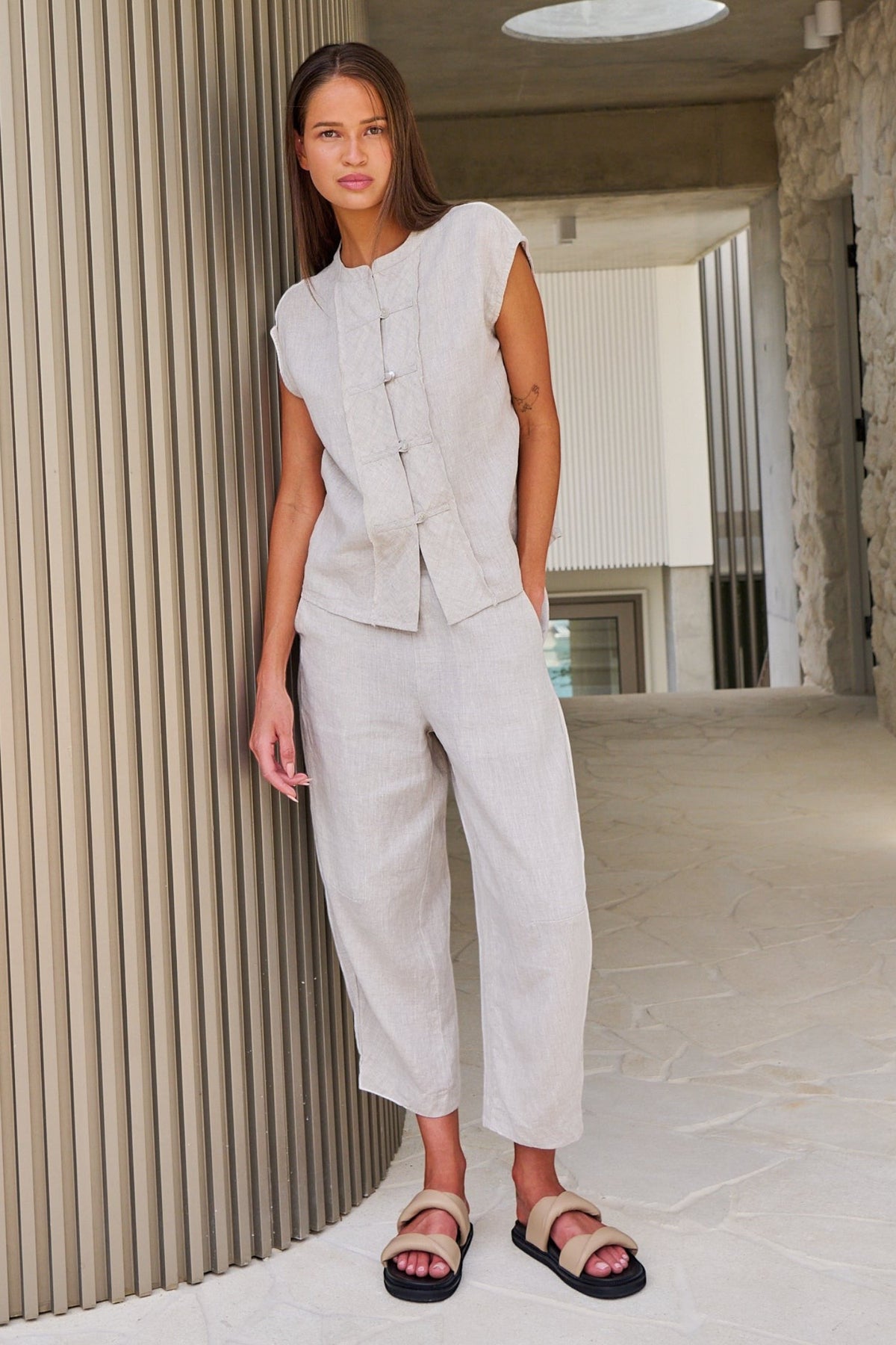 Model wearing ELSHAM BOUTIQUE sand linen cropped tapered pants with an elasticated waistband and side pockets.