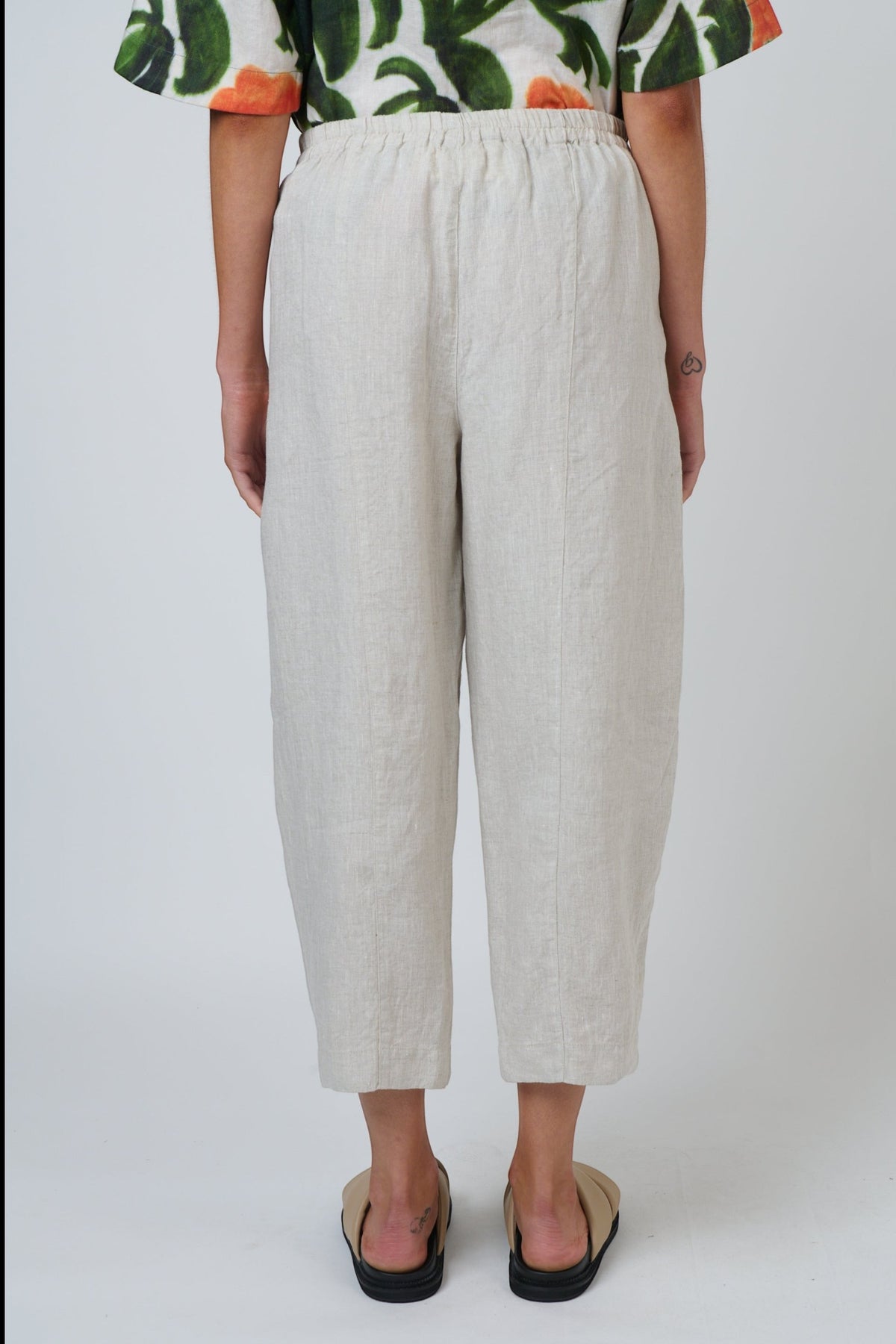 ELSHAM BOUTIQUE sand linen cropped tapered pants with an elasticated waistband and side pockets, back view.