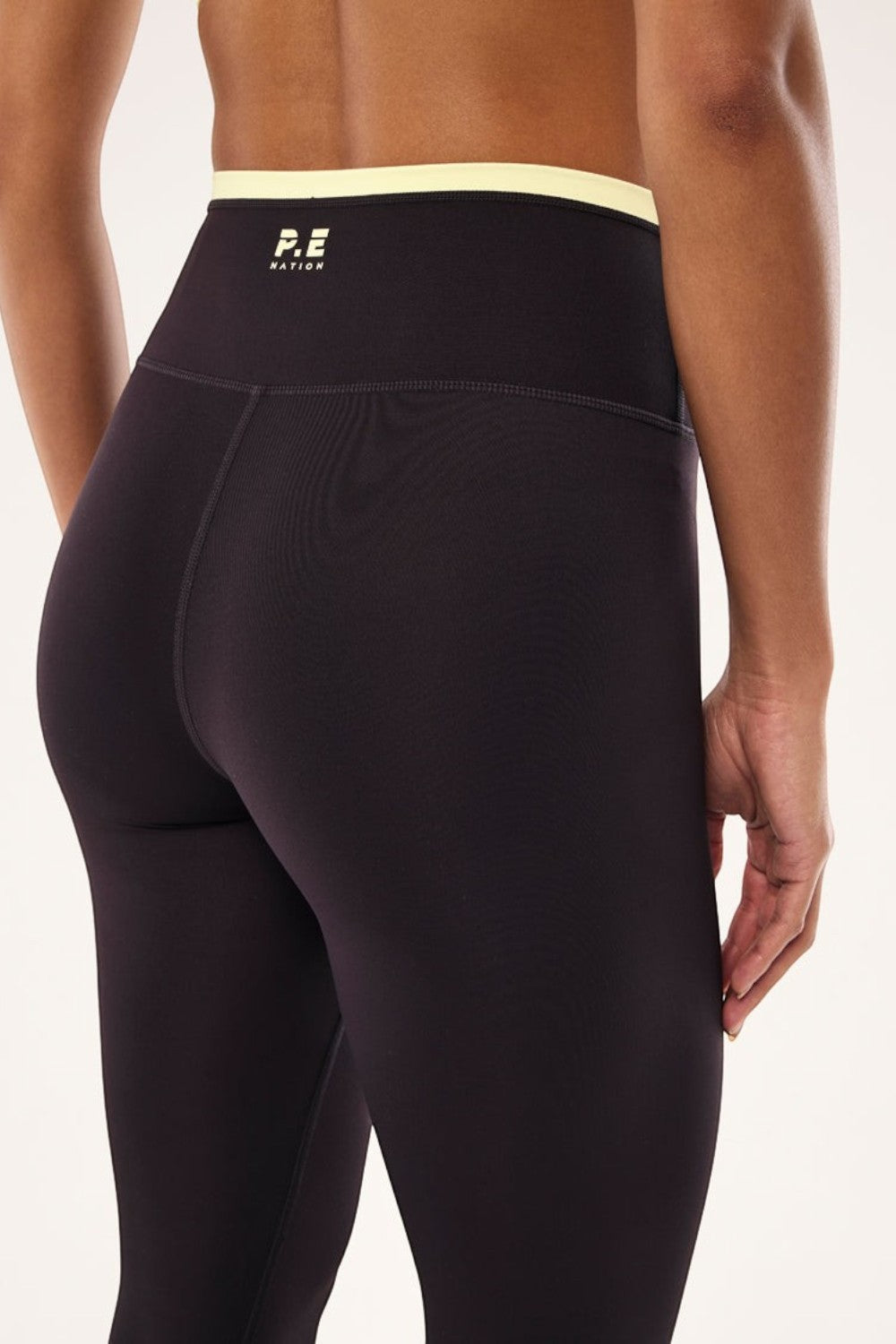 ELSHAM BOUTIQUE Vita full length leggings in black bean with a soft yellow high-rise waistband and P.E Nation logo.