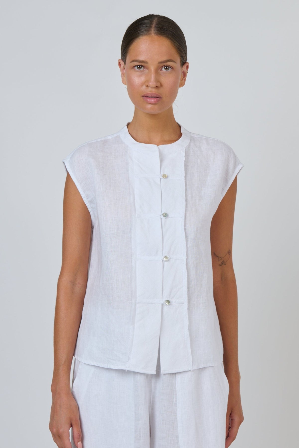 ELSHAM BOUTIQUE white linen sleeveless top with a collarless neckline and quilted button-through placket.