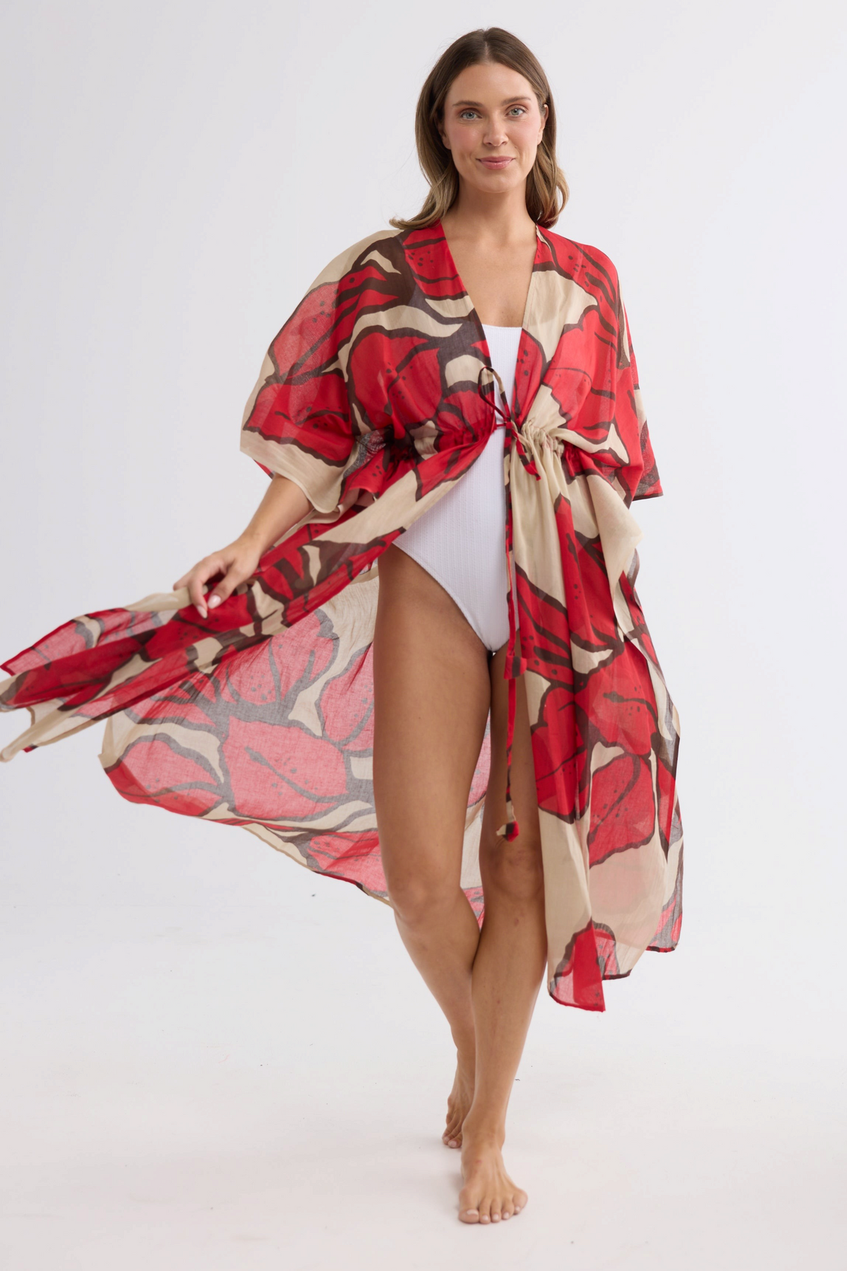 Model wearing ELSHAM BOUTIQUE Asta long cotton kaftan in crimson floral print with an adjustable waist tie