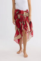 ELSHAM BOUTIQUE Stella sarong scarf in crimson floral print cotton worn as a beach wrap on a white background