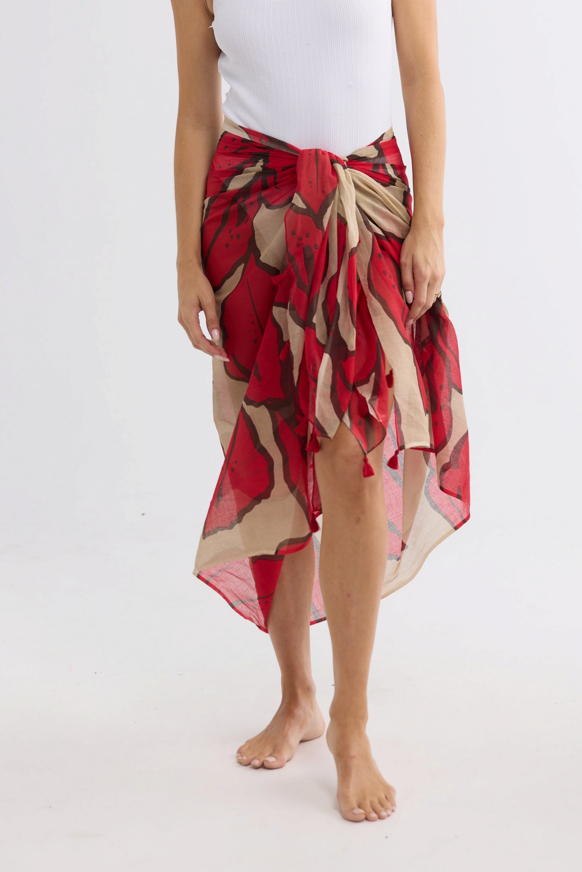 ELSHAM BOUTIQUE Stella sarong scarf in crimson floral print cotton worn as a beach wrap on a white background