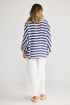 ELSHAM BOUTIQUE navy striped oversized linen shirt with exaggerated sleeves, worn with white trousers, back view.
