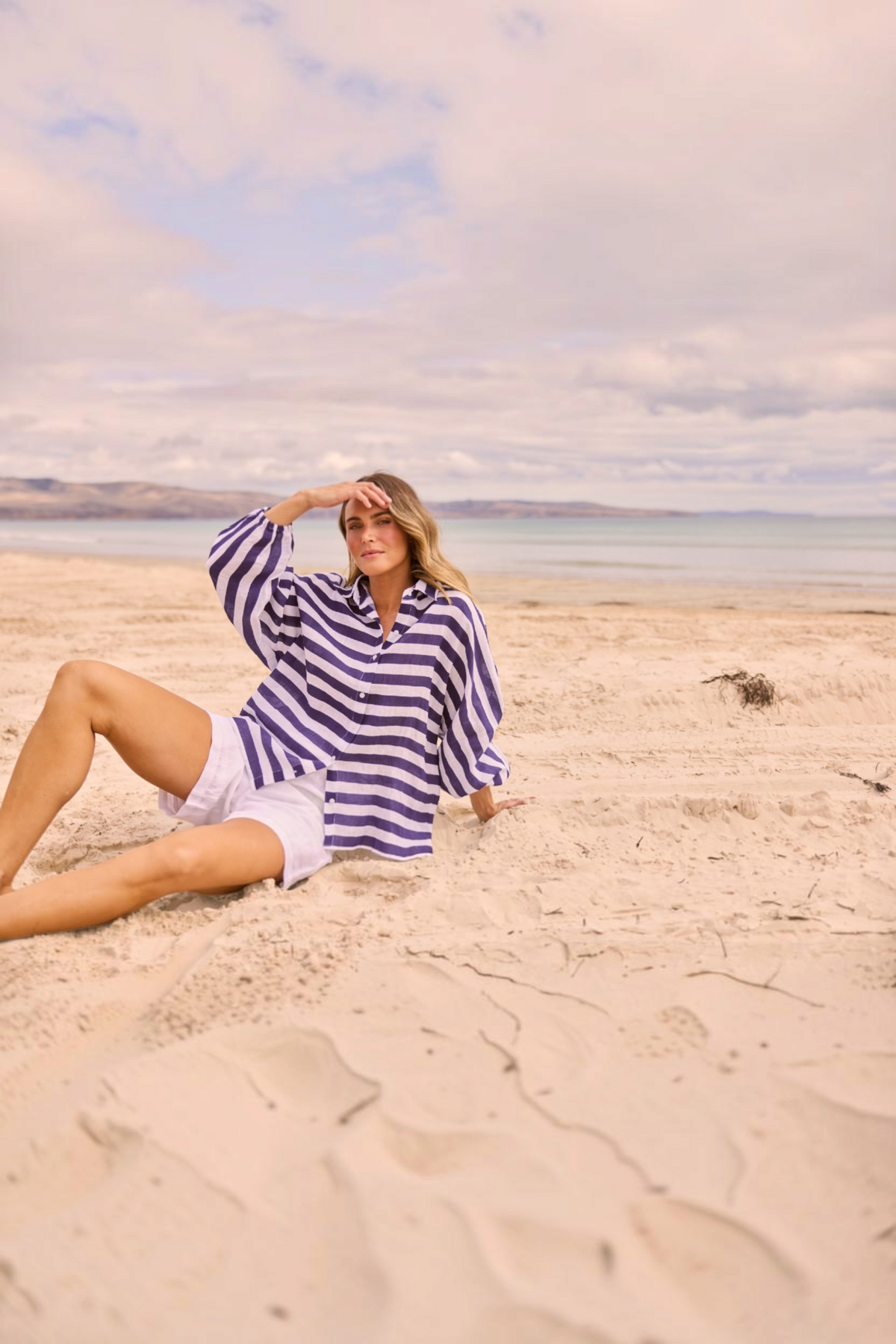 ELSHAM BOUTIQUE Cliffside navy striped oversized linen shirt with button front and elasticated cuffs on a sandy beach