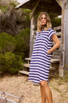 ELSHAM BOUTIQUE navy and white striped cotton tunic with cap sleeves, collared neckline, and pockets on a beach.