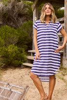 ELSHAM BOUTIQUE navy and white striped cotton tunic with collared neckline and hi-lo hem worn by a woman outdoors.