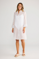 ELSHAM BOUTIQUE white cotton shirt dress with short sleeves and button front, worn by a smiling model.