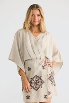 ELSHAM BOUTIQUE natural linen wrap dress with kimono sleeves, V-neckline, and brown embroidered geometric patterns.