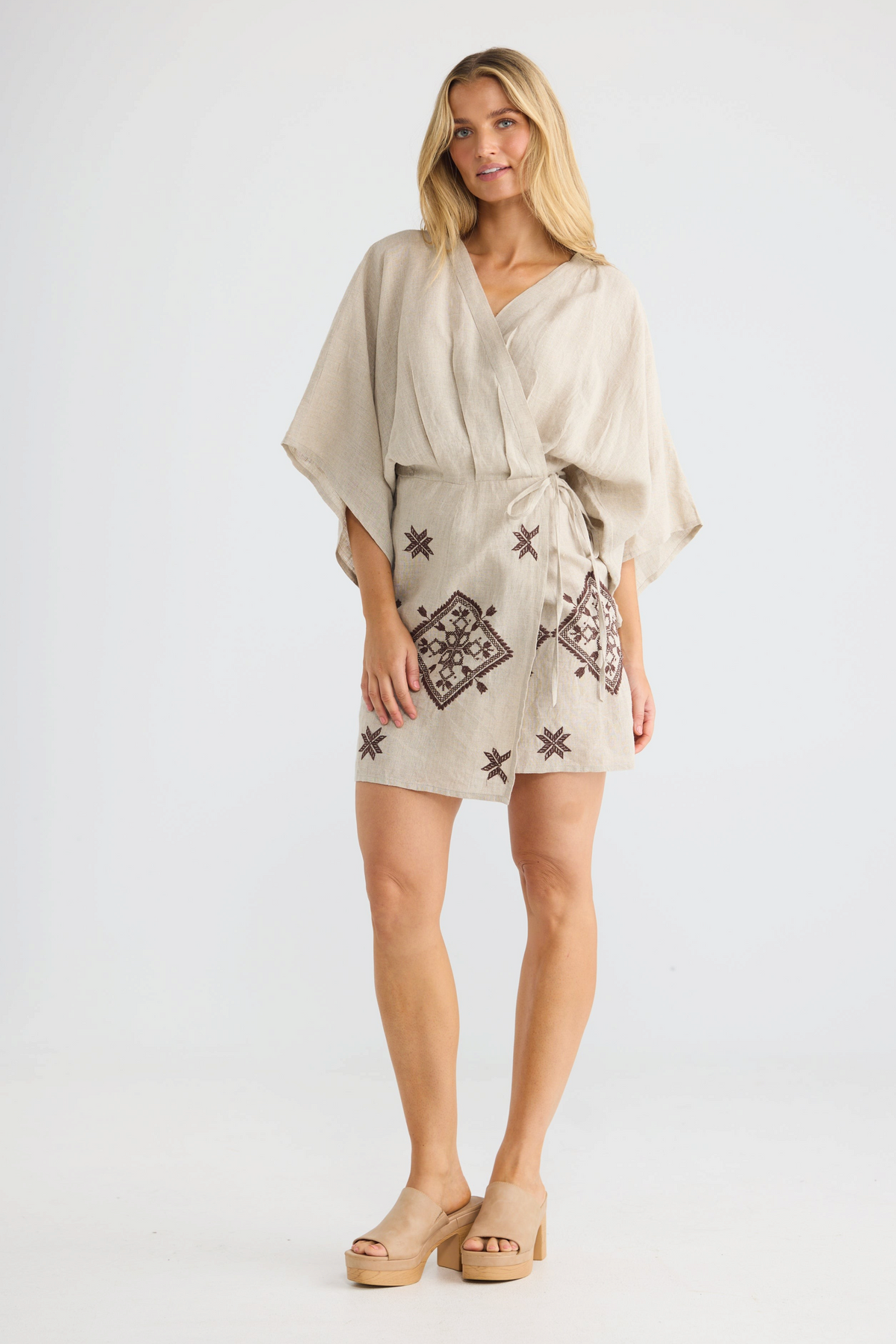 ELSHAM BOUTIQUE Jeanne natural linen wrap dress with kimono sleeves and brown embroidered details on a model