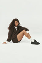 ELSHAM BOUTIQUE model wearing coffee brown Stellar 5 inch bike shorts and a brown fleece zip-up jacket