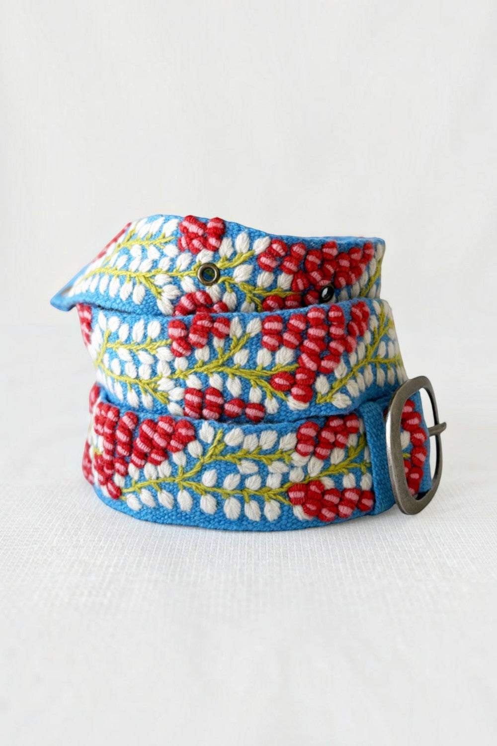 ELSHAM BOUTIQUE wool belt featuring blue fabric with red and white embroidered berry vine patterns and metal buckle.