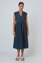 ELSHAM BOUTIQUE navy pinstripe linen midi dress with V-neck, cap sleeves, and drop gathered waist on a model.