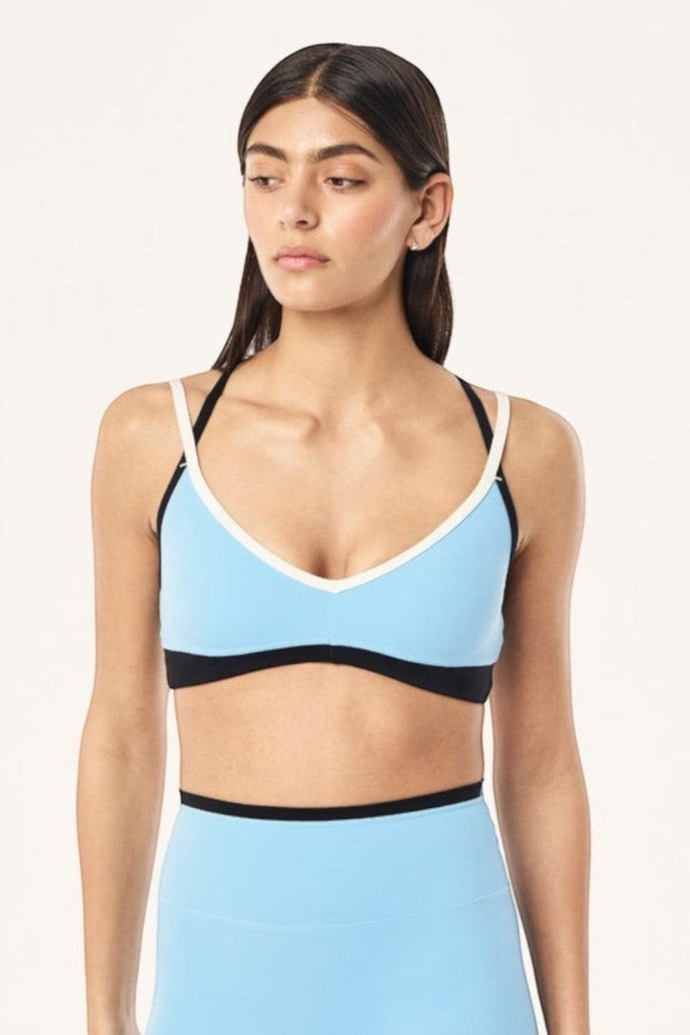 Model wearing ELSHAM BOUTIQUE Paramount sports bra in Alaskan blue and black with V-neck and adjustable double straps.