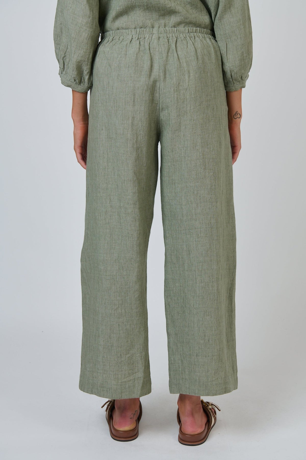 Back view of ELSHAM BOUTIQUE GA398 wide-leg linen trousers in artichoke green with a gathered back waistband.